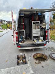 Odprt jašek na cesti in kombi z opremo za pregled